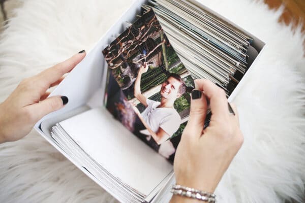 a woman holding a photograph of something that she took from a box