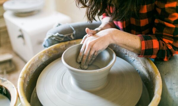 a woman making a pot out of clay