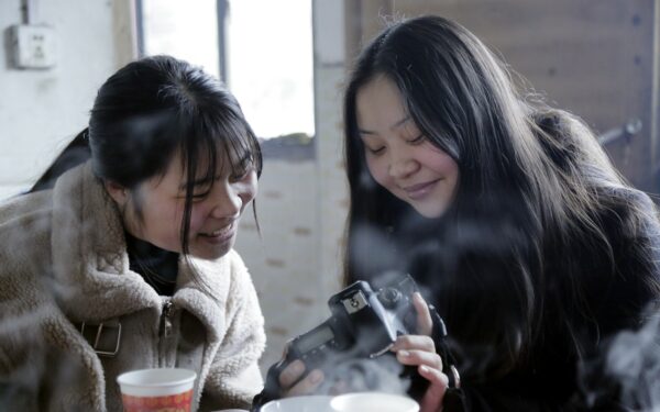 two asian girls looking at pictures from a DSLR camera