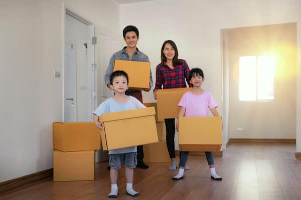 happy asian family with cardboard boxes in their new house